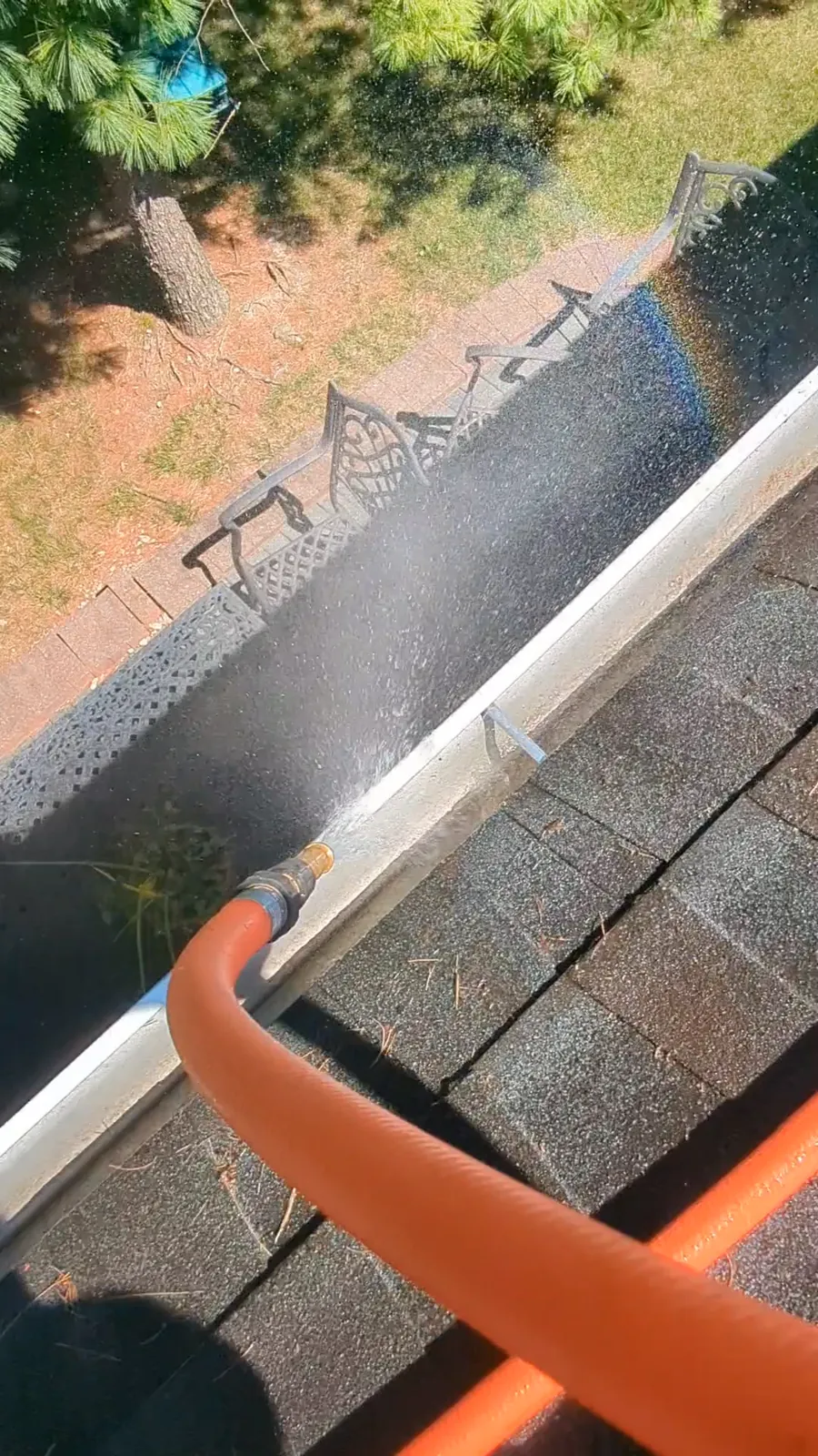 Flushing a cleared gutter with a hose until it runs clear, on a job in Barnegat, NJ