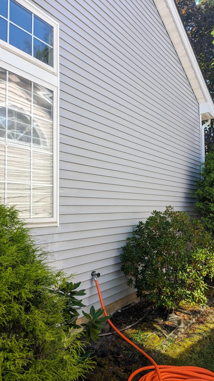 After: Soft wash house washing, September 5, 2025. Algae and mildew streaks on the shaded side, then the same wall rinsed clean.
