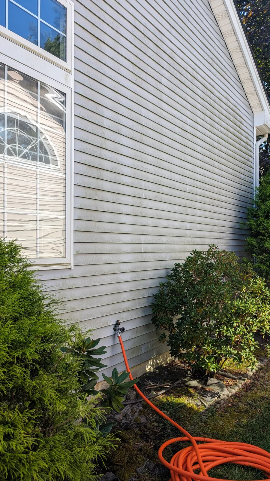 Before: Soft wash house washing, September 5, 2025. Algae and mildew streaks on the shaded side, then the same wall rinsed clean.