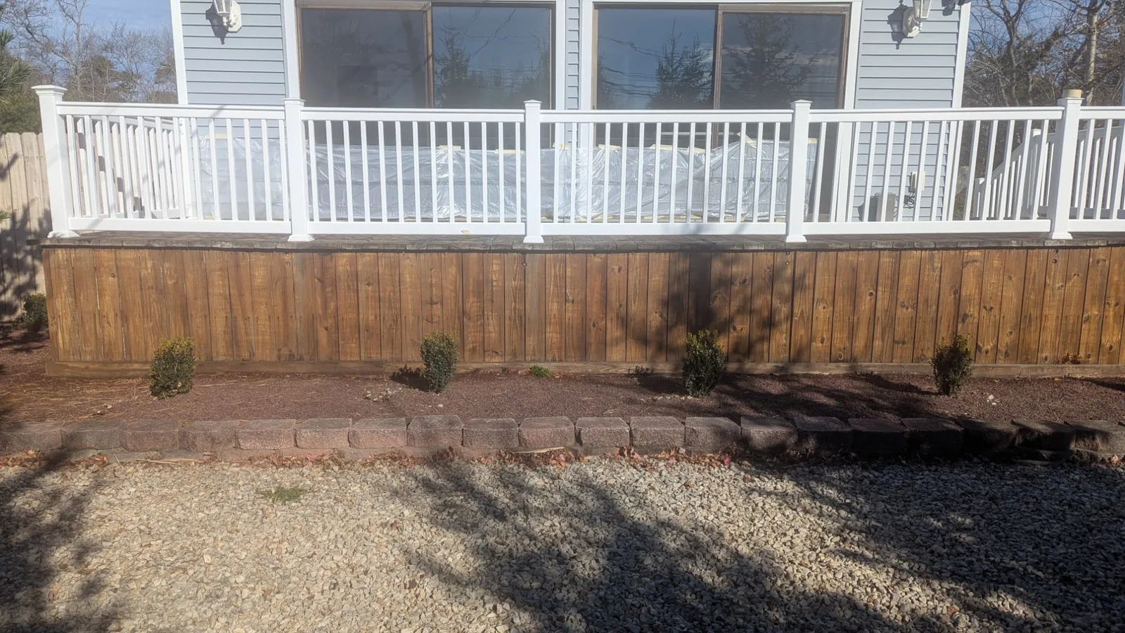 Deck skirting on a Brick, NJ home after power washing and staining, with the white railing above it