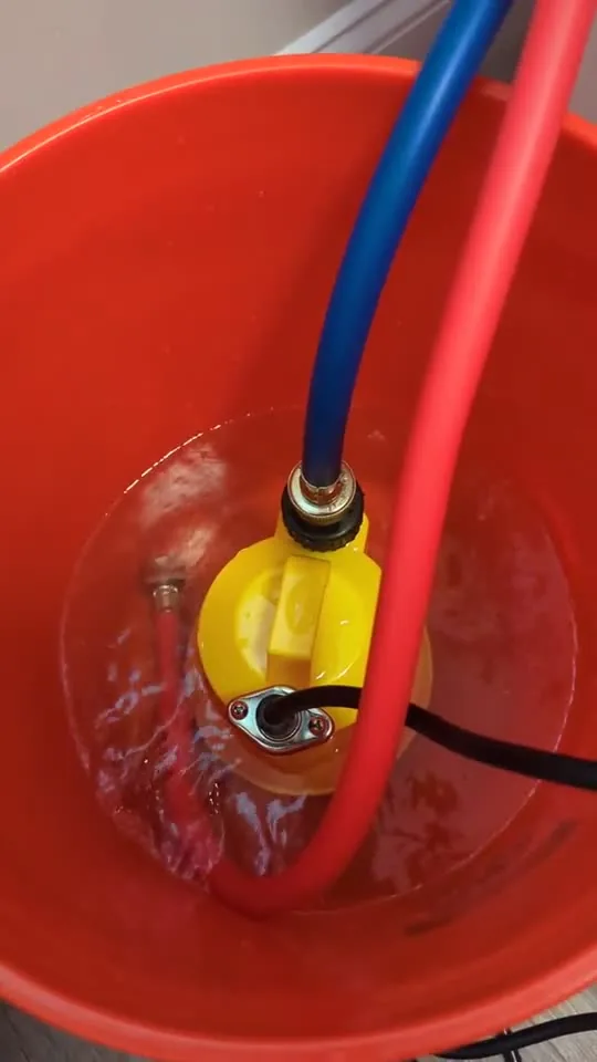 A pump and hoses in a bucket during a water heater flush